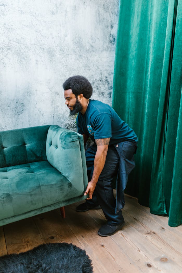 Man lifting a stylish green couch in a modern interior, highlighting moving services and home decor.