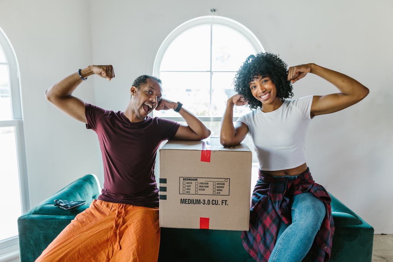 gallery-1 Joyful couple flexing muscles while unpacking in their new home.