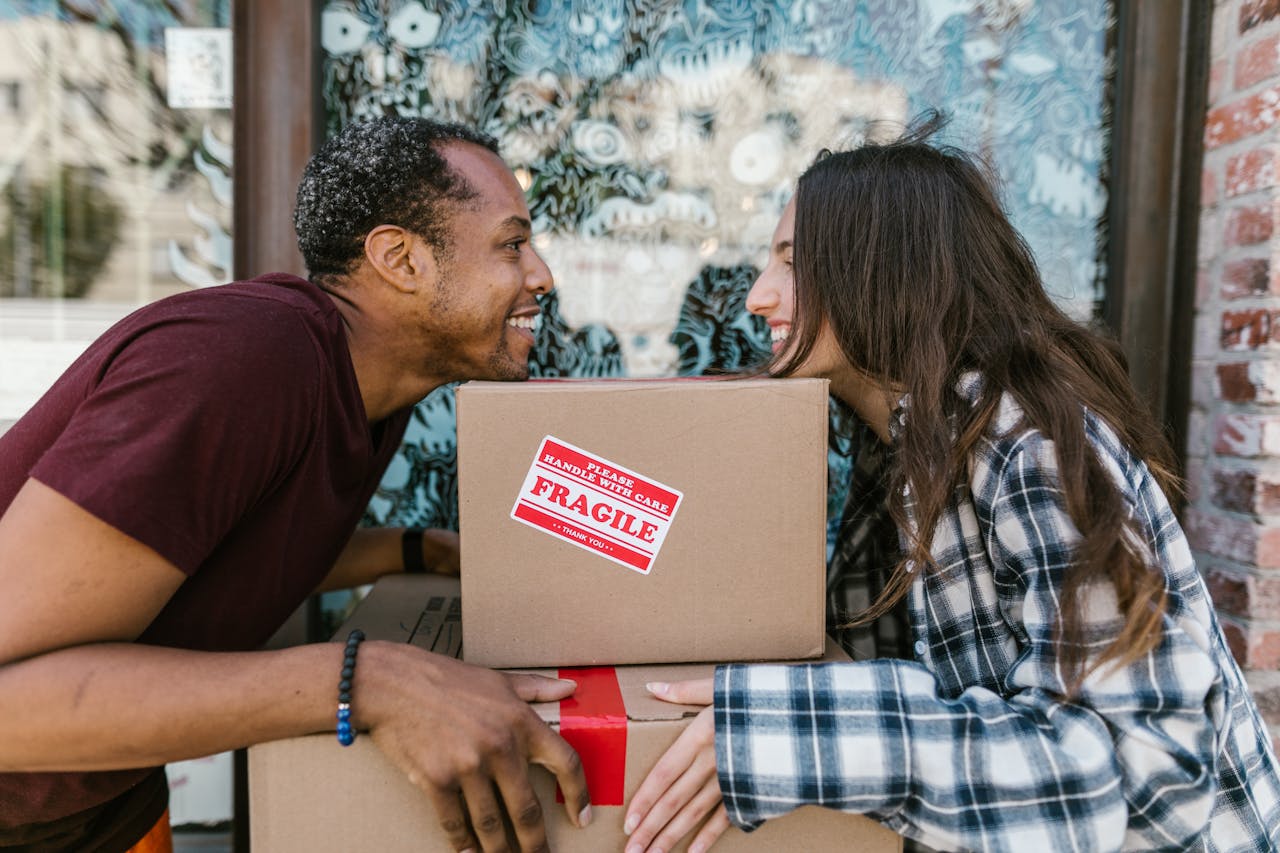 gallery-3 A joyful couple enjoying the moving day experience while carrying boxes labeled 'Fragile'.